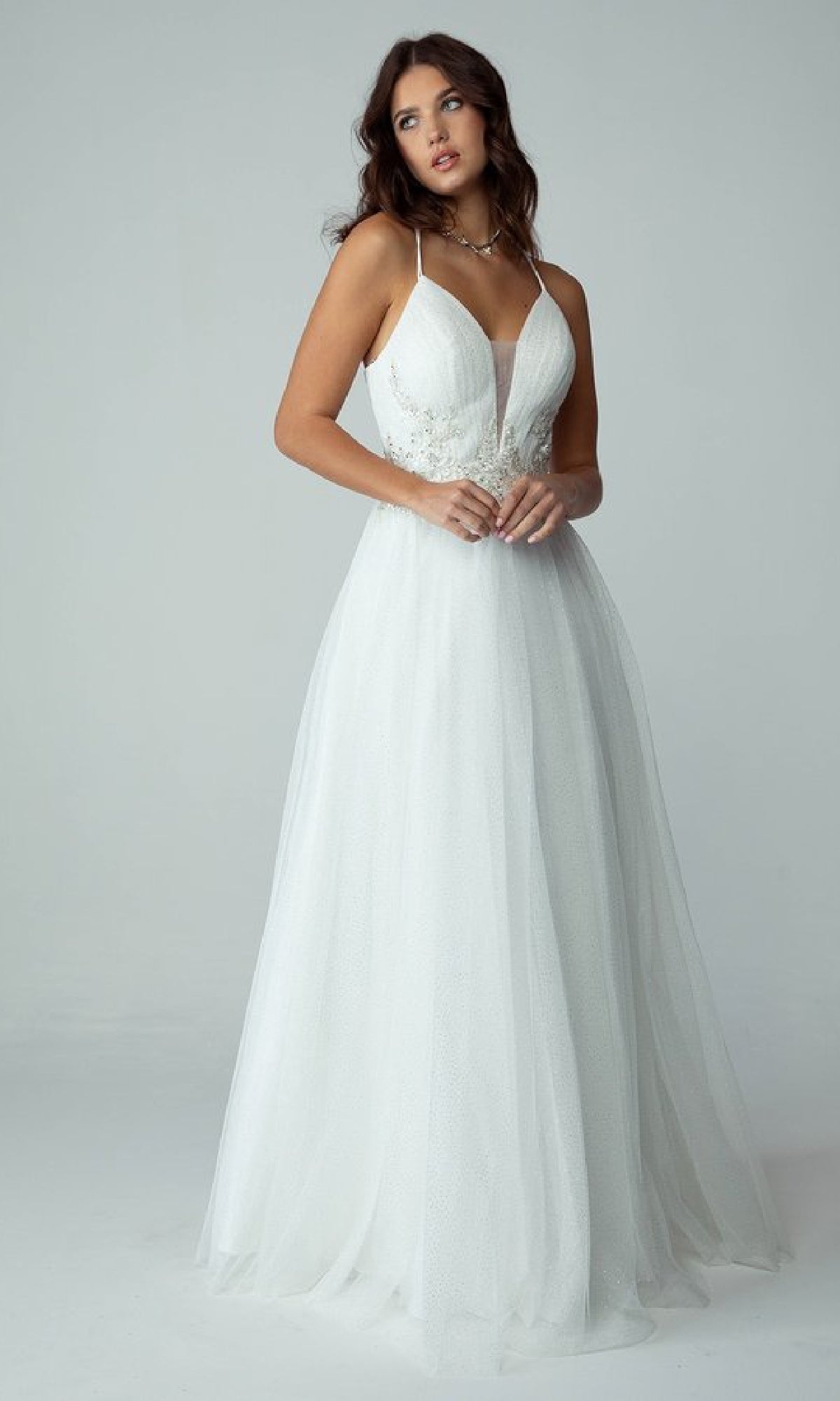 A woman poses in a studio wearing the Eureka 9797: a Lace-Up Long Shimmer Prom Dress featuring thin straps, a fitted bodice, and a flowing floor-length skirt.